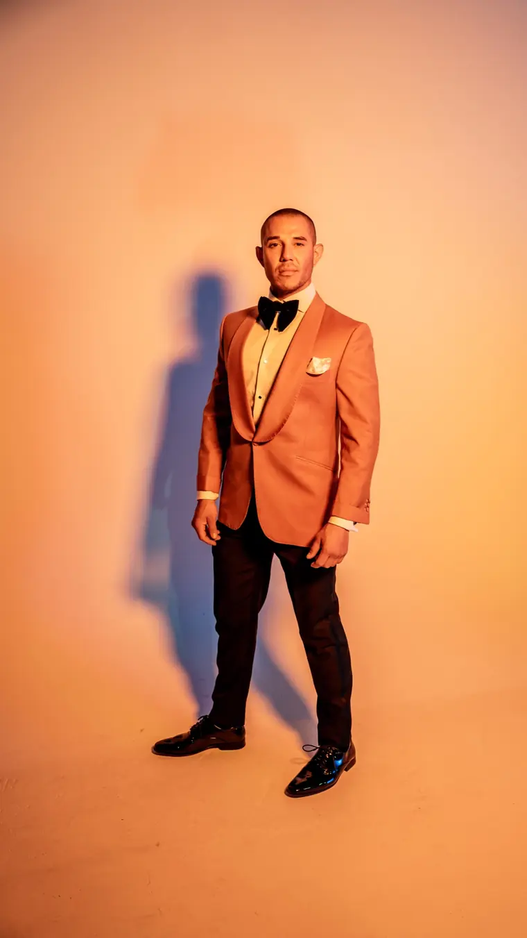 A Lusso MTM terracotta tuxedo on a model against a warm backdrop